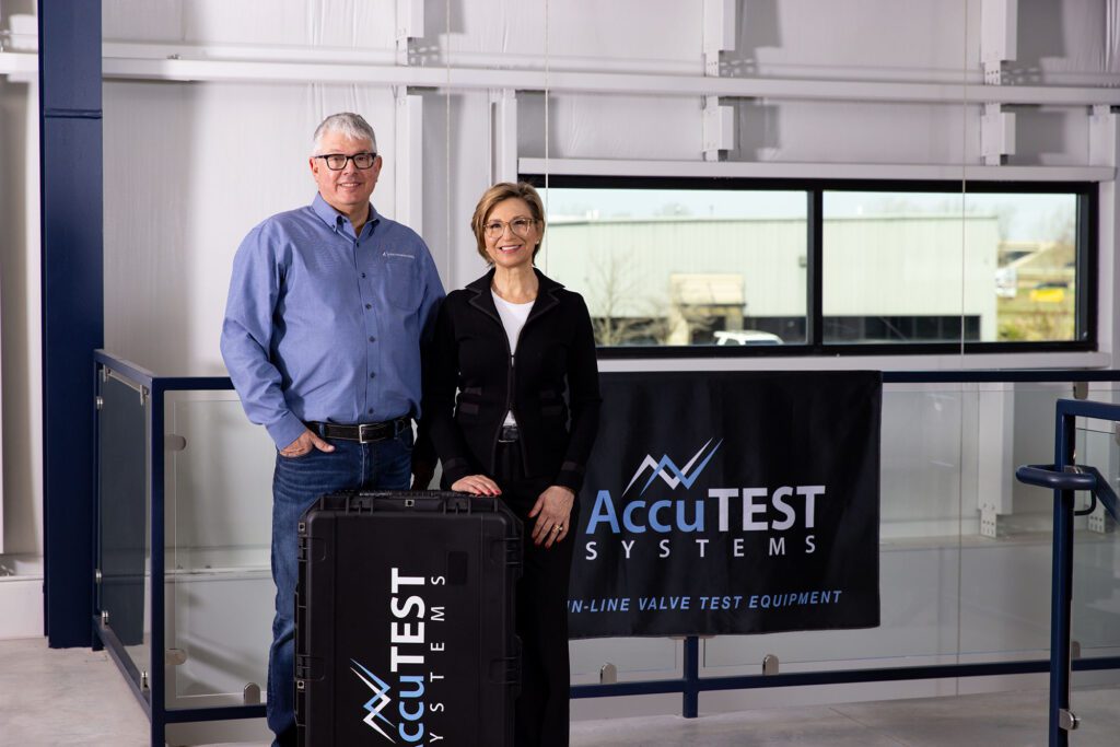 Man and woman AccuTEST experts standing with AccuTEST equipment and signage